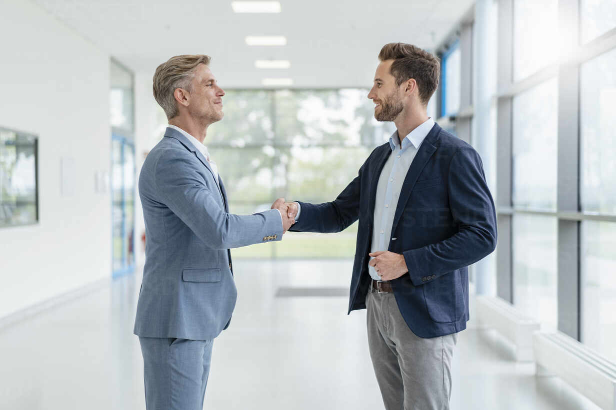 Two businessmen shaking hands in a passageway